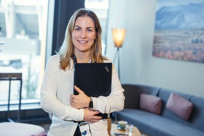 Kvinne som holder en pc og smiler til kamera